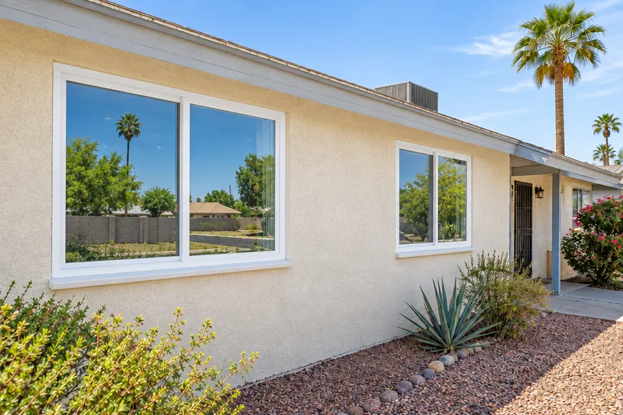 The same Tempe home after window replacement: new white vinyl dual-pane windows with clean frames and fresh sealant, same wall and yard, tidy and bright